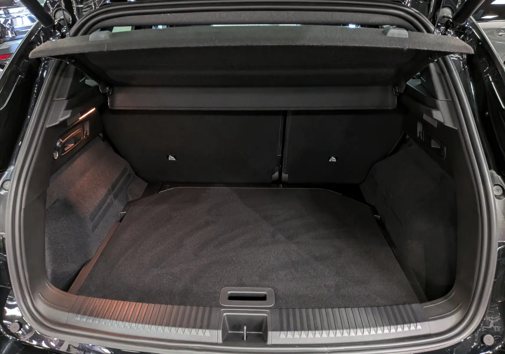 Coffre ouvert vu de l'arrière d'un Renault Austral noir, montrant un espace de chargement propre et spacieux.