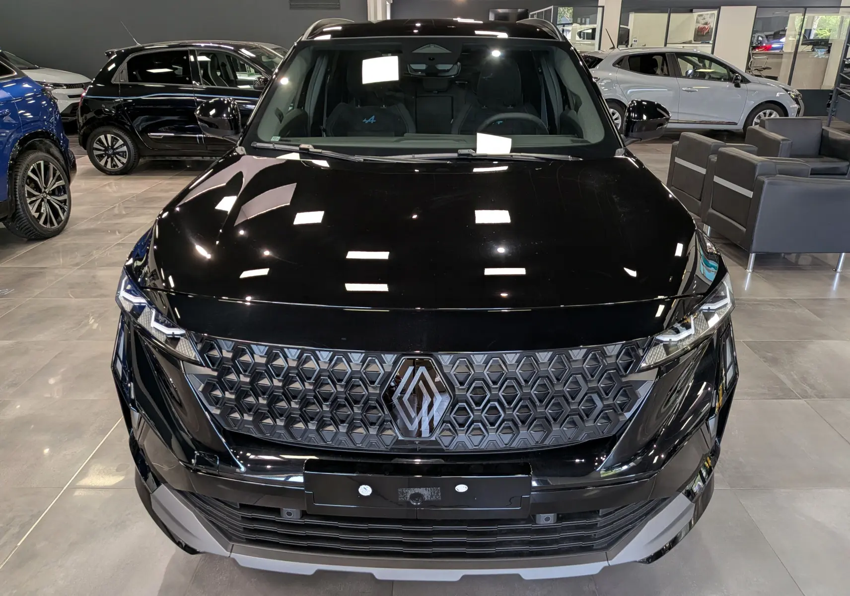Vue avant rapprochée du Renault Austral noir full hybrid E-Tech 200 ch avec calandre hexagonale et logo Alpine visible.