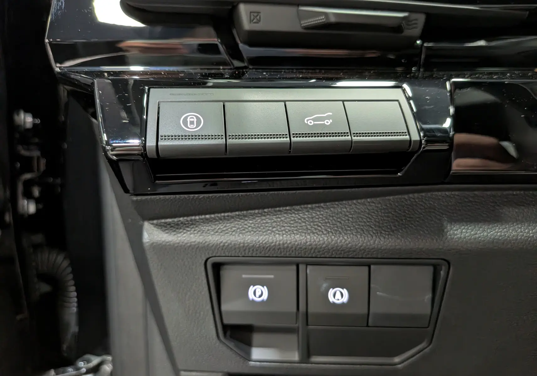 Gros plan sur les boutons de commande noirs du tableau de bord du Renault Austral noir, avec icônes éclairées.