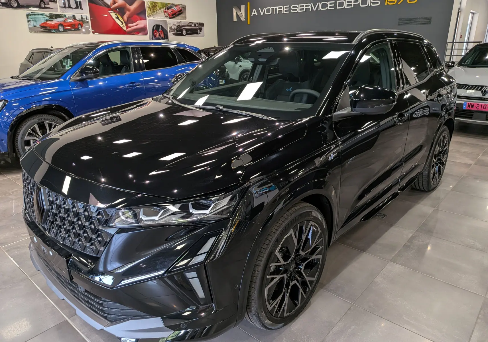 Renault Austral full hybrid noir en 3/4 avant droit, avec calandre distinctive et jantes noires stylées en showroom.