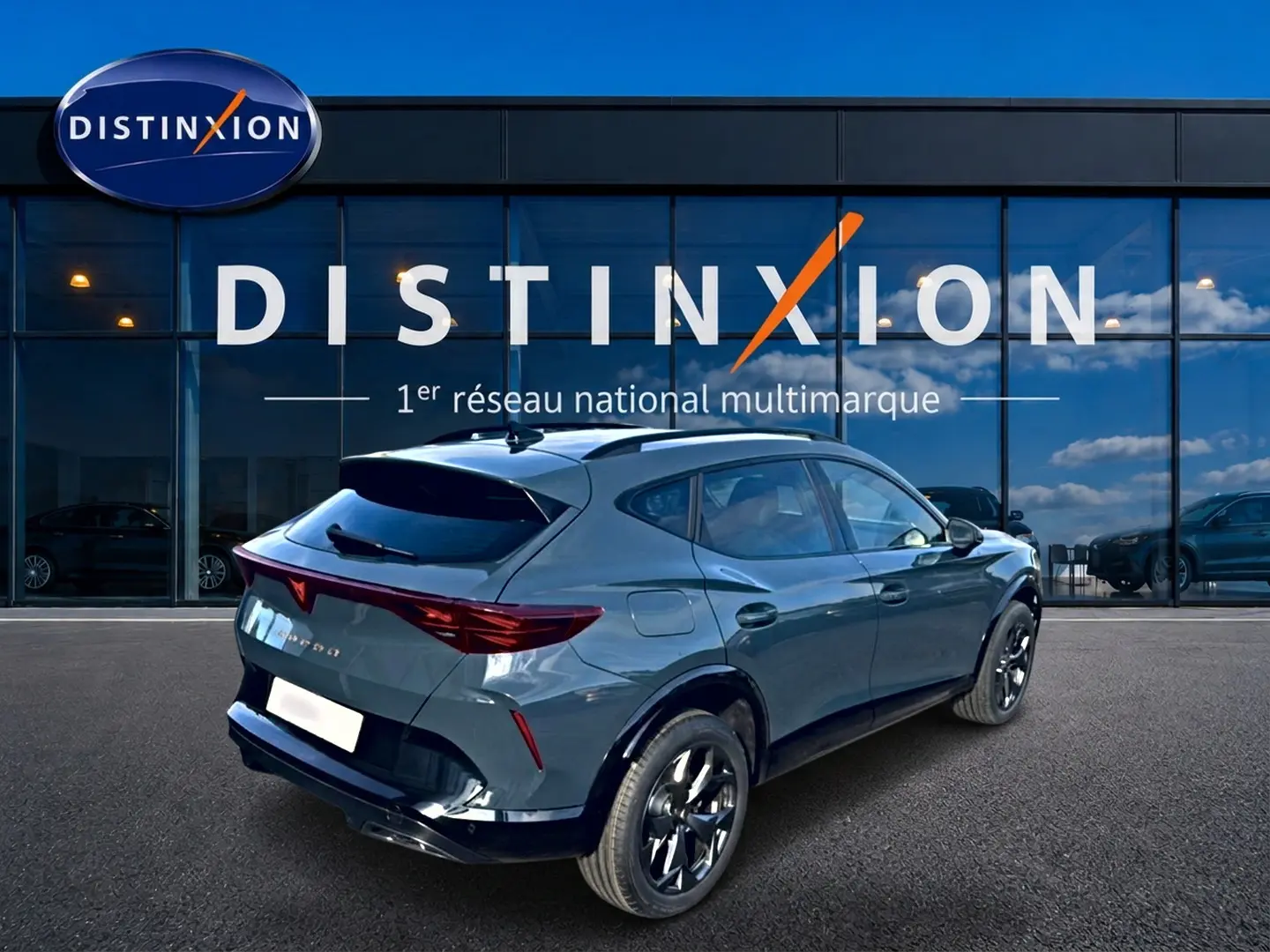 Vue 3/4 arrière droite d'une CUPRA Formentor bleu fjord avec jantes noires devant un showroom Distinxion.