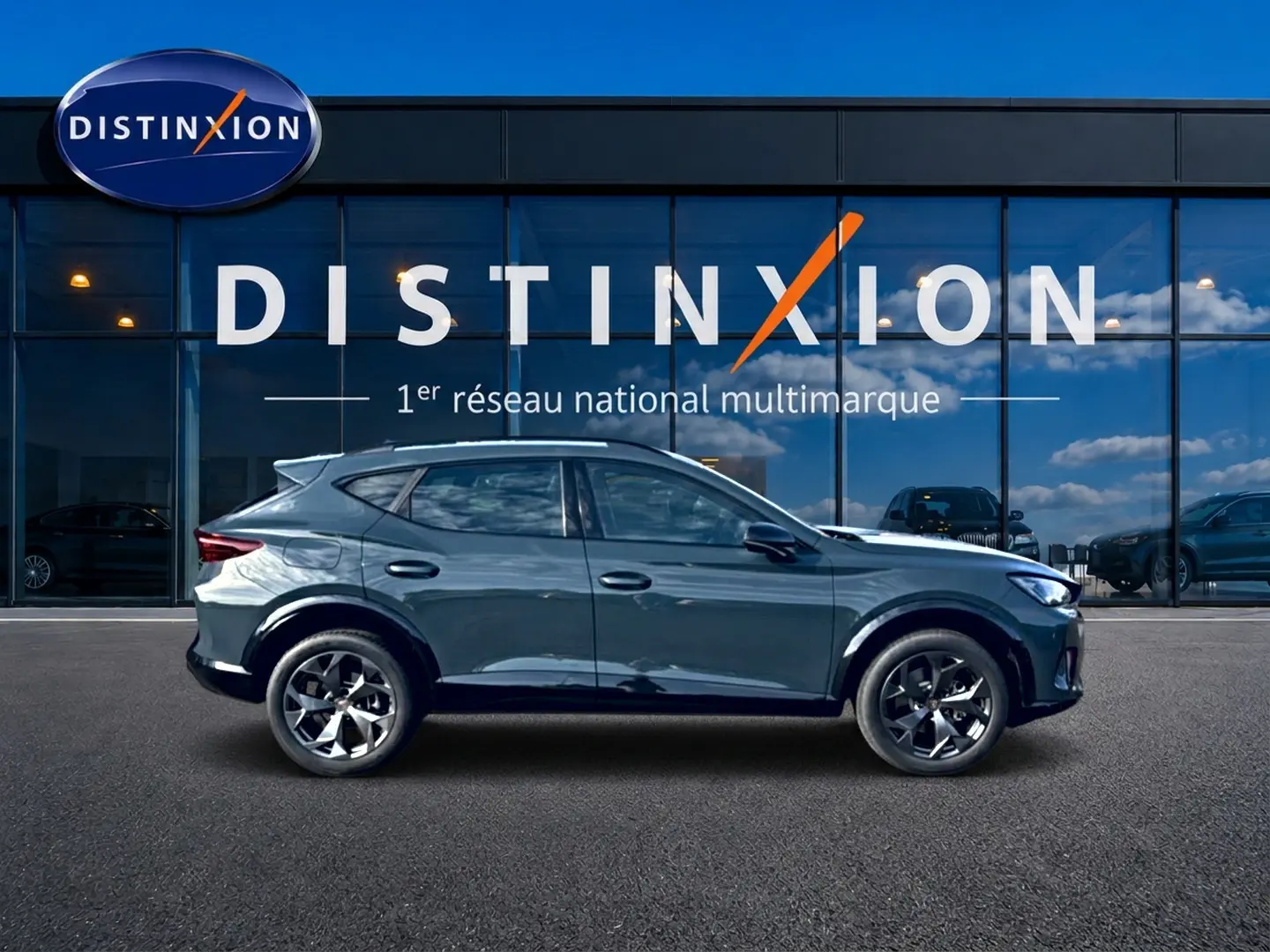 Vue latérale droite d'un CUPRA Formentor bleu fjord 2026 avec jantes 18 pouces devant une vitrine Distinxion.