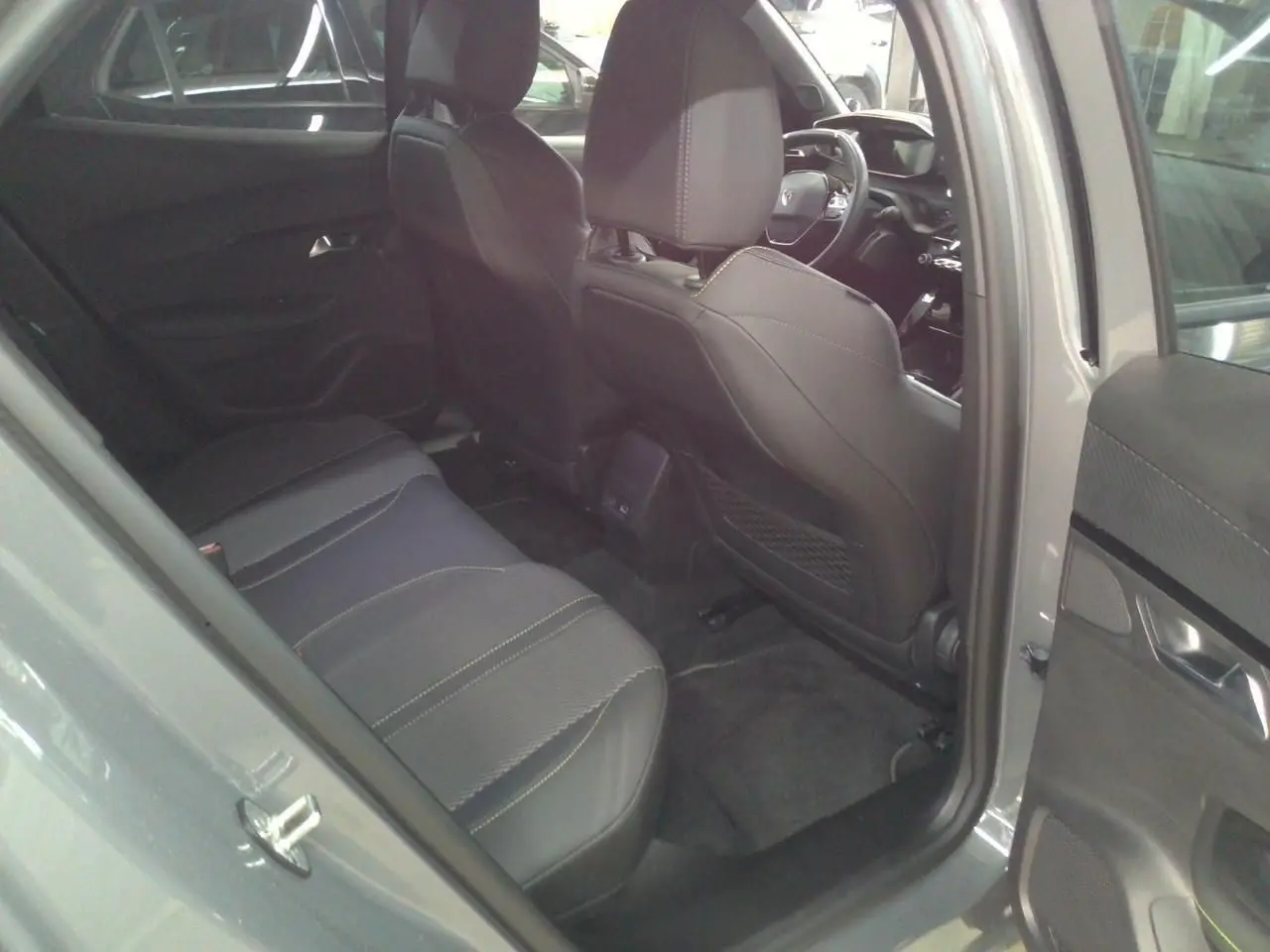 Vue intérieure arrière côté gauche du Peugeot 2008 1.2 Hybrid 145ch GT gris Selenium, sièges en cuir noir avec surpiqûres claires.