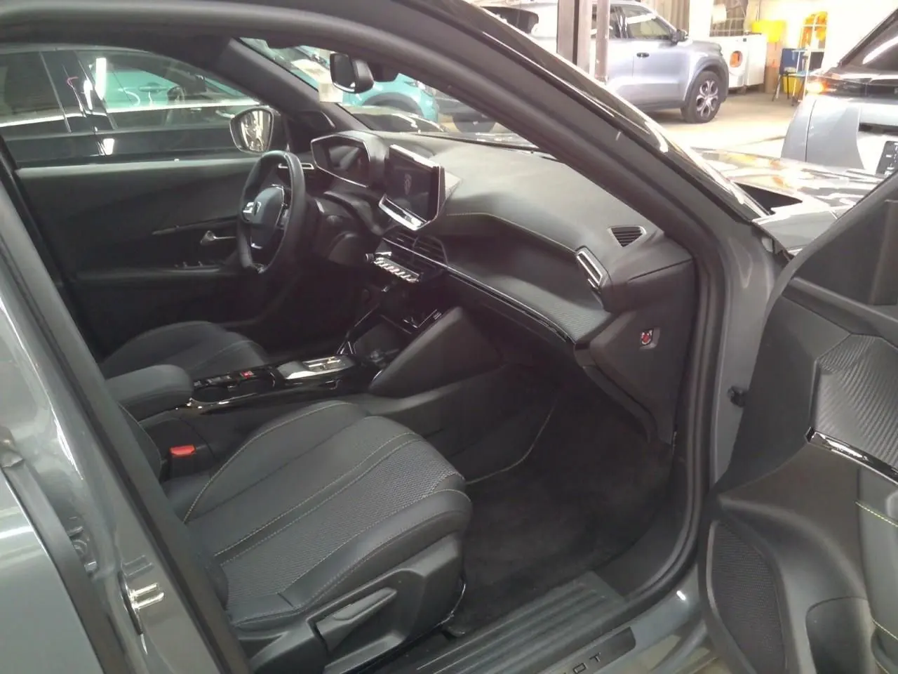 Intérieur avant droit du Peugeot 2008 gris selenium 2025, avec tableau de bord moderne et sièges tissu noir.