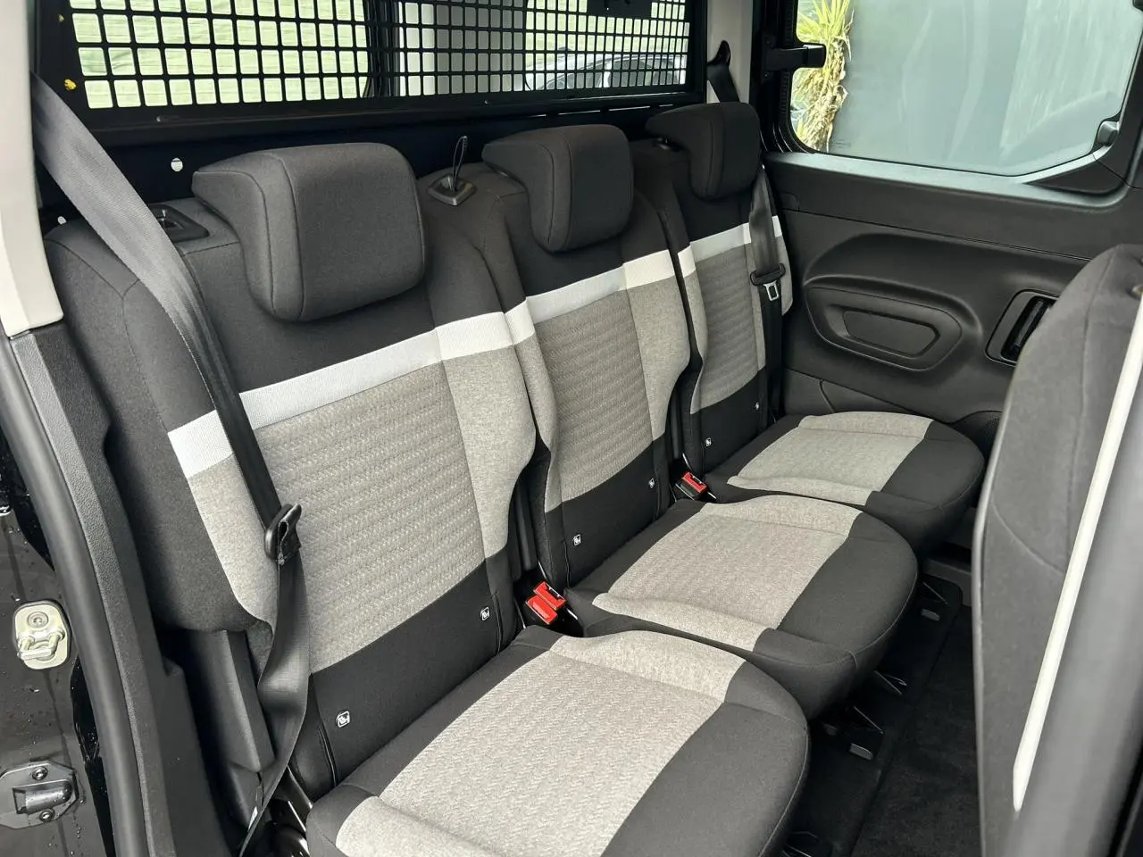 Vue latérale droite des trois sièges arrière indépendants gris et noirs du Citroën Berlingo Multispace 2025, avec ceinture et porte latérale ouverte.