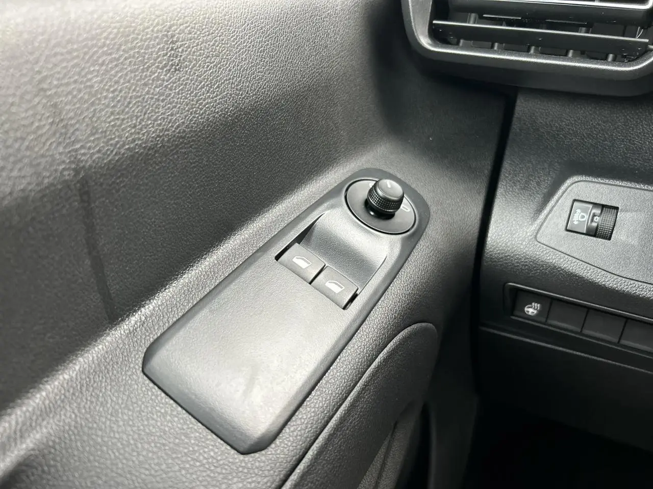 Gros plan sur les commandes de lève-vitres et réglage des rétroviseurs côté gauche du Citroën Berlingo Multispace noir Perla.