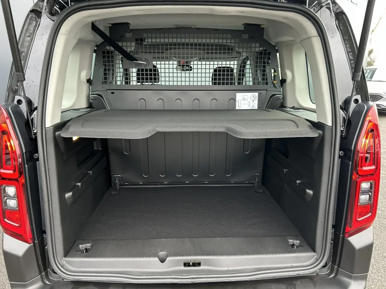 Vue arrière ouverte du Citroën Berlingo Multispace noir Perla, montrant le coffre spacieux avec tablette de séparation.
