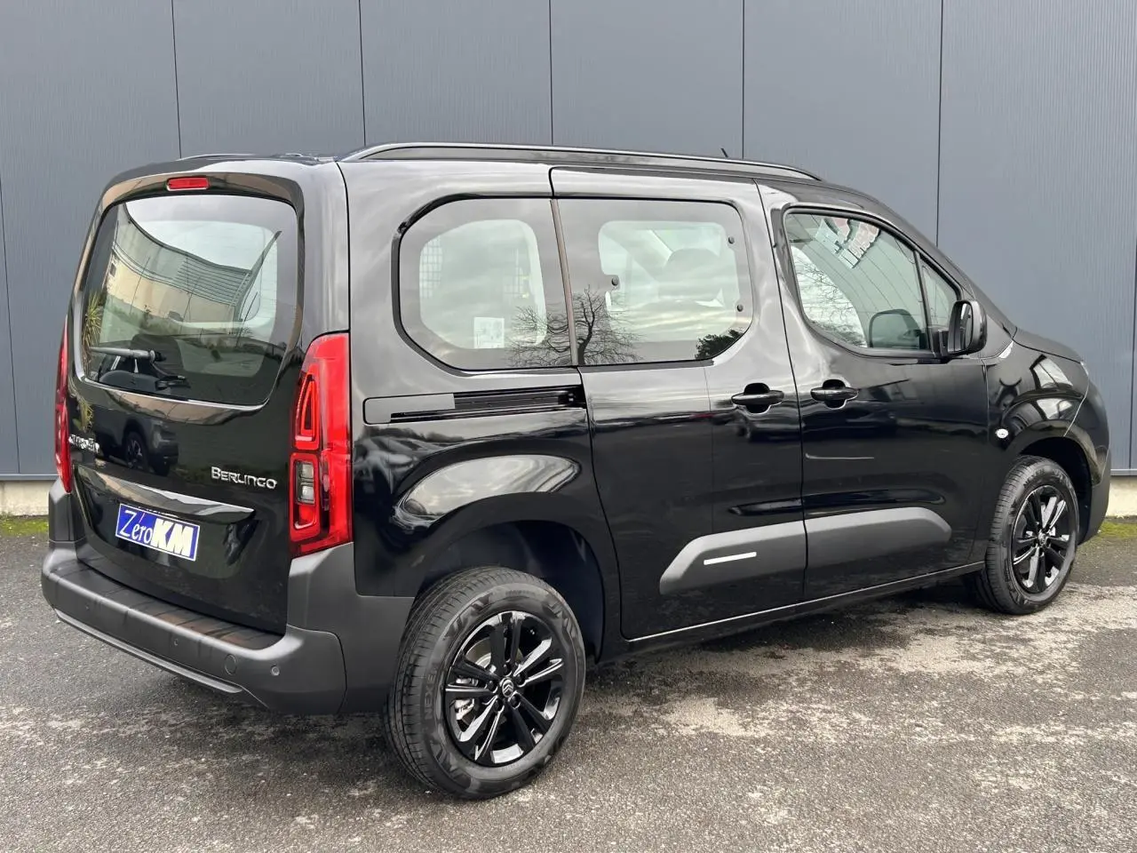 Vue 3/4 arrière droite du Citroën Berlingo Multispace noir Perla avec jantes alliage noires et barres de toit.