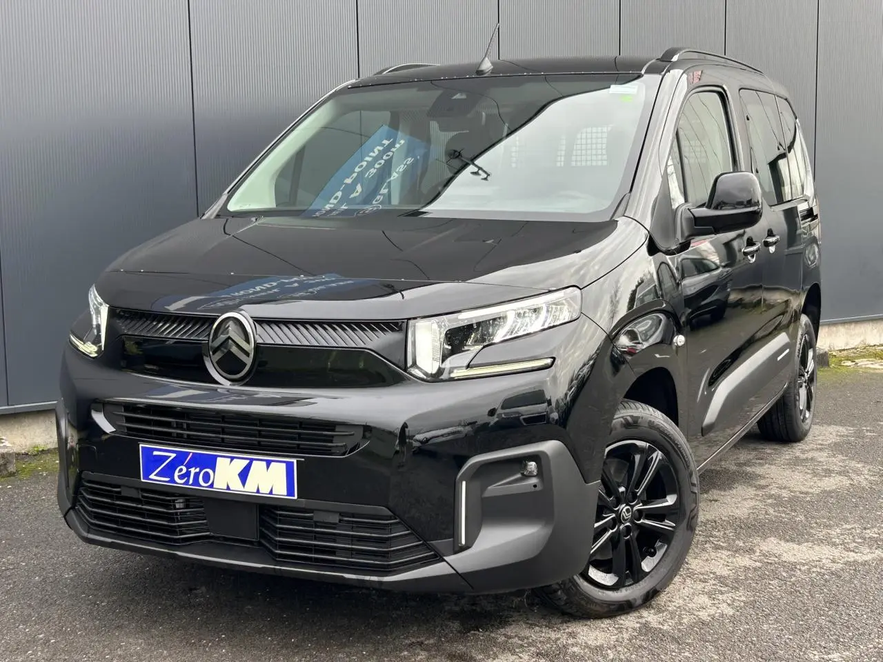 Vue 3/4 avant droit du Citroën Berlingo Multispace noir Perla avec jantes alliage noires et barres de toit.
