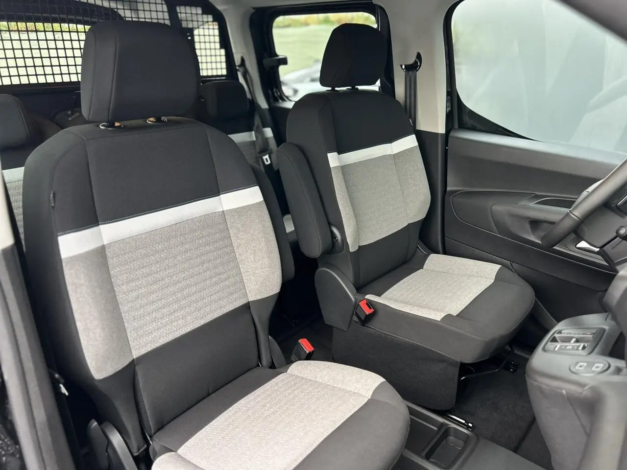 Vue intérieure avant du Citroën Berlingo Multispace 2025, sièges tissu bicolore gris et noir avec accoudoirs.