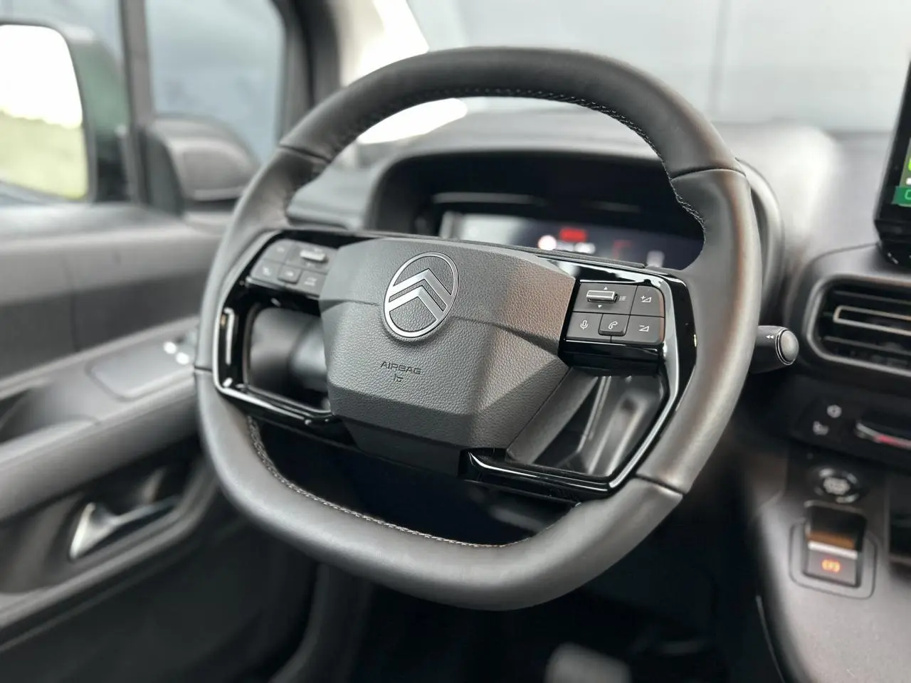 Gros plan sur le volant cuir multifonctions noir du Citroën Berlingo Multispace 2025 avec tableau de bord et commandes visibles.