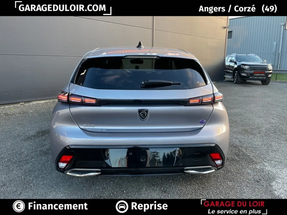 Vue arrière d'une Peugeot 308 gris foncé 2024 avec feux LED allumés et double sortie d'échappement chromée.