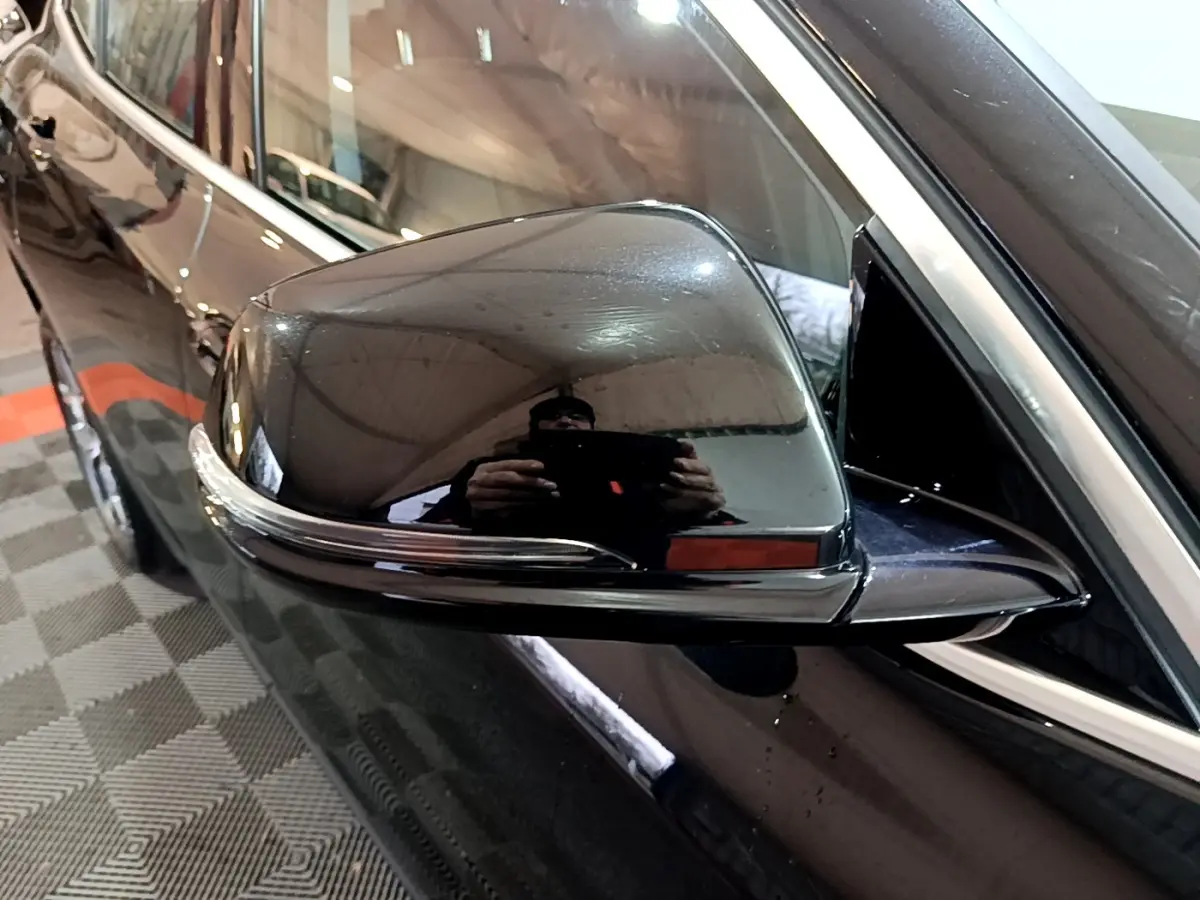 Gros plan sur le rétroviseur côté conducteur noir brillant d’un BMW X2 sDrive18i Lounge 2023.