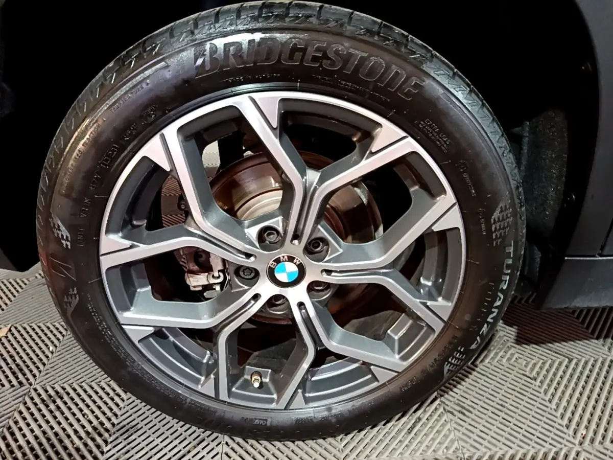 Gros plan sur la roue avant droite noire d’une BMW X2 2023 avec jante alliage gris foncé et pneu Bridgestone.
