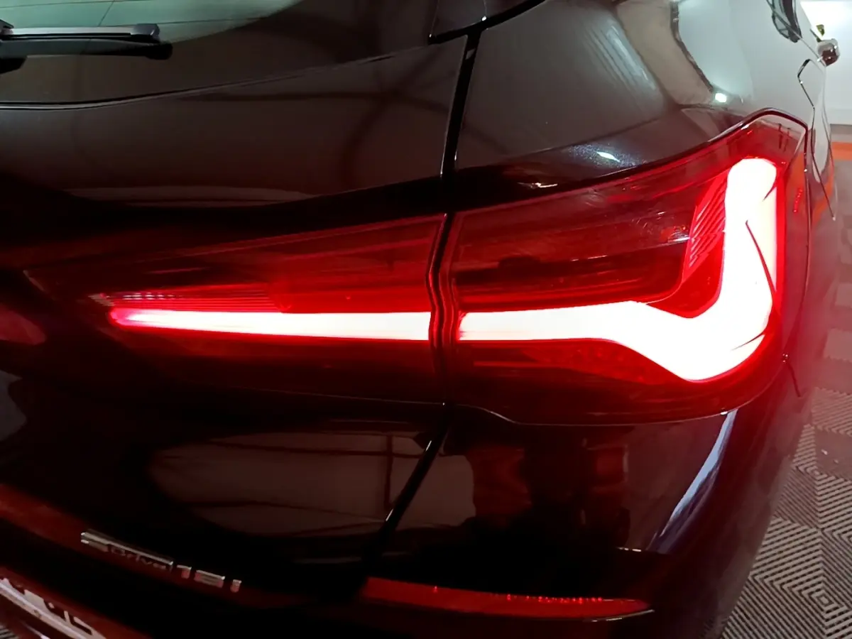 Gros plan sur le feu arrière droit allumé d’un BMW X2 sDrive18i Lounge noir, soulignant la ligne lumineuse distinctive.
