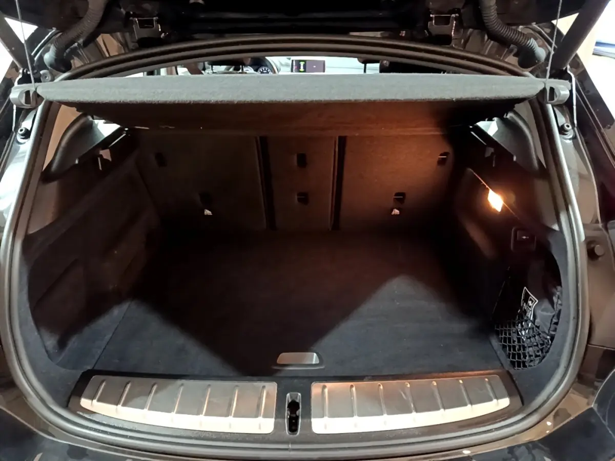 Coffre ouvert noir du BMW X2 sDrive18i Lounge 2023, montrant l’espace de chargement avec éclairage intérieur.