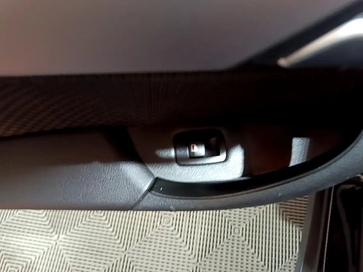 Détail du bouton de verrouillage sur la porte intérieure noire d'une BMW X2 sDrive18i Lounge 2023.