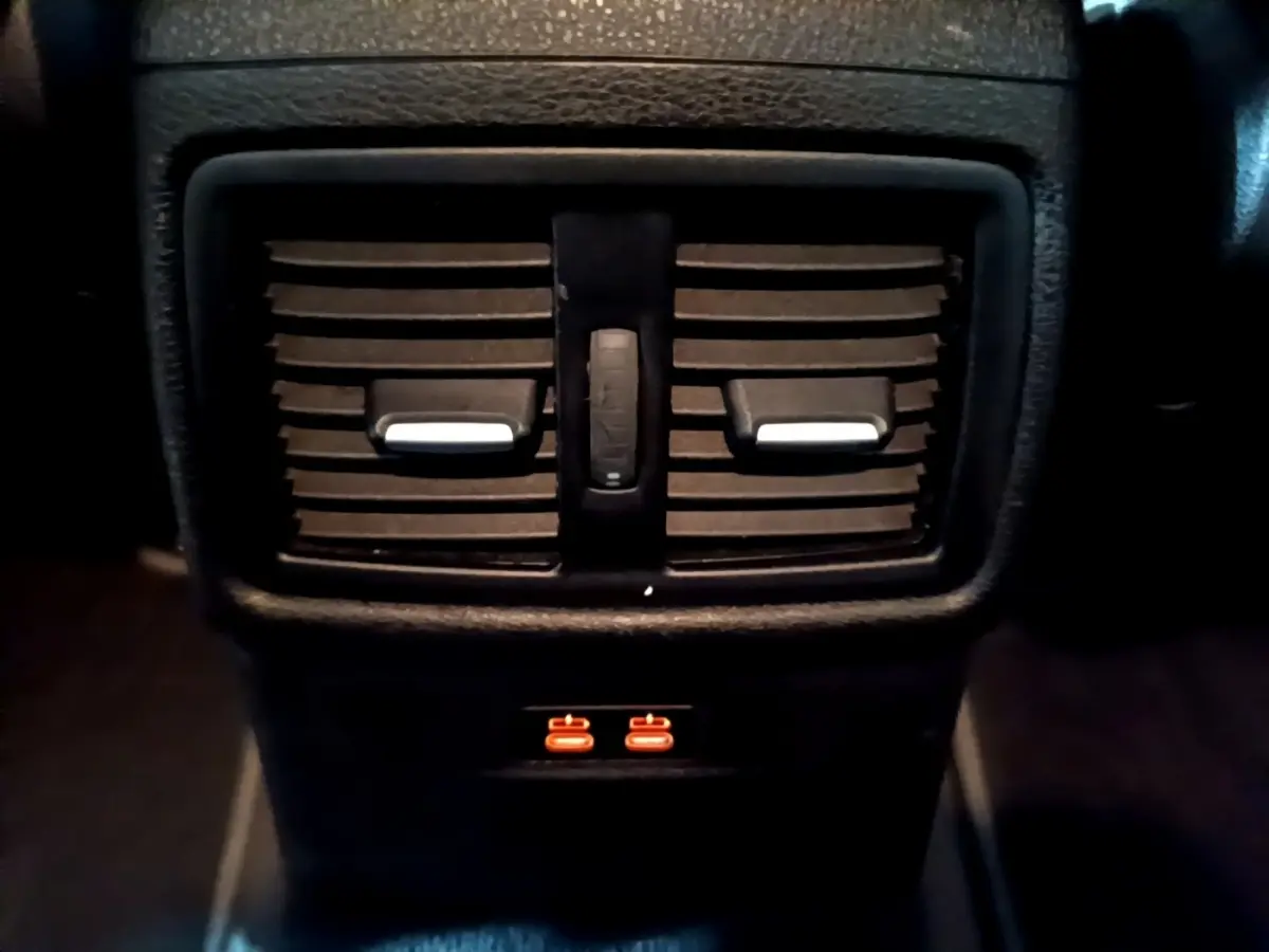 Gros plan sur les aérateurs arrière noirs et les ports USB éclairés en orange du BMW X2 sDrive18i Lounge 2023.