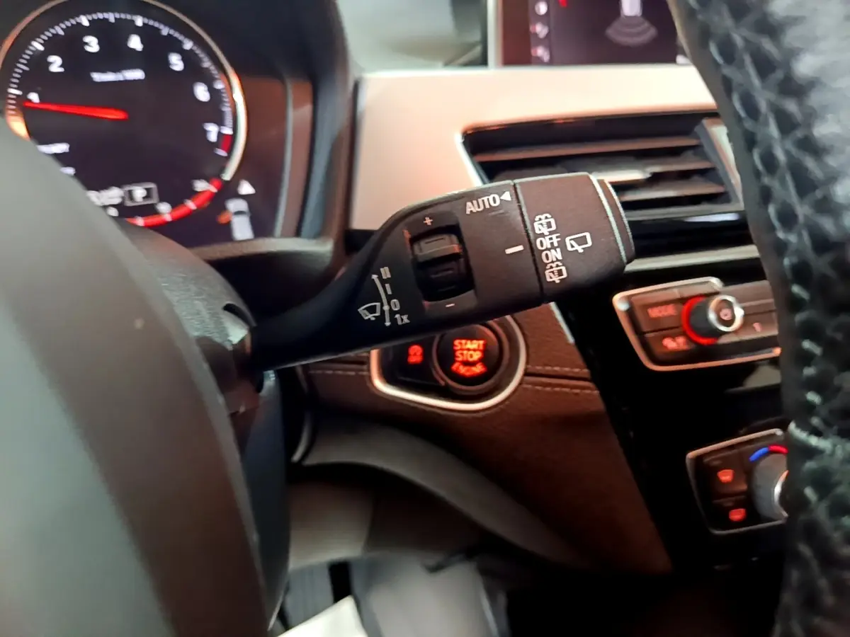 Gros plan sur la commande d’essuie-glace et le bouton start/stop dans l’habitacle noir du BMW X2 2023.