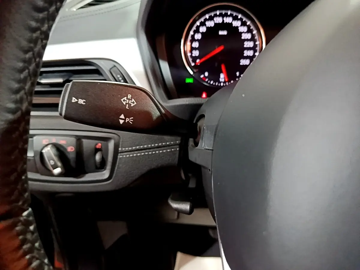 Gros plan sur la commande de clignotants à gauche du volant noir dans l’habitacle du BMW X2 sDrive18i 2023.