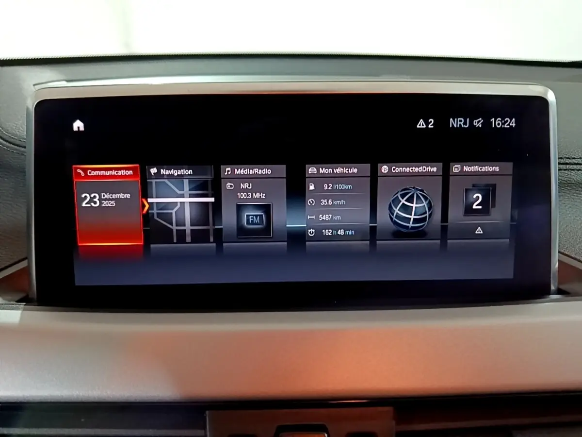 Écran central tactile de la BMW X2 sDrive18i Lounge 2023 affichant navigation, radio et informations véhicule.