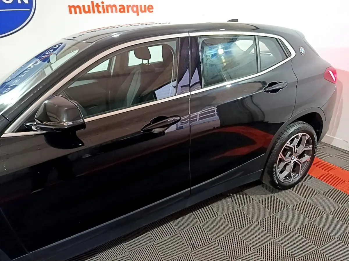 BMW X2 sDrive18i Lounge noir vue de profil côté gauche, soulignant les jantes et les vitres teintées.