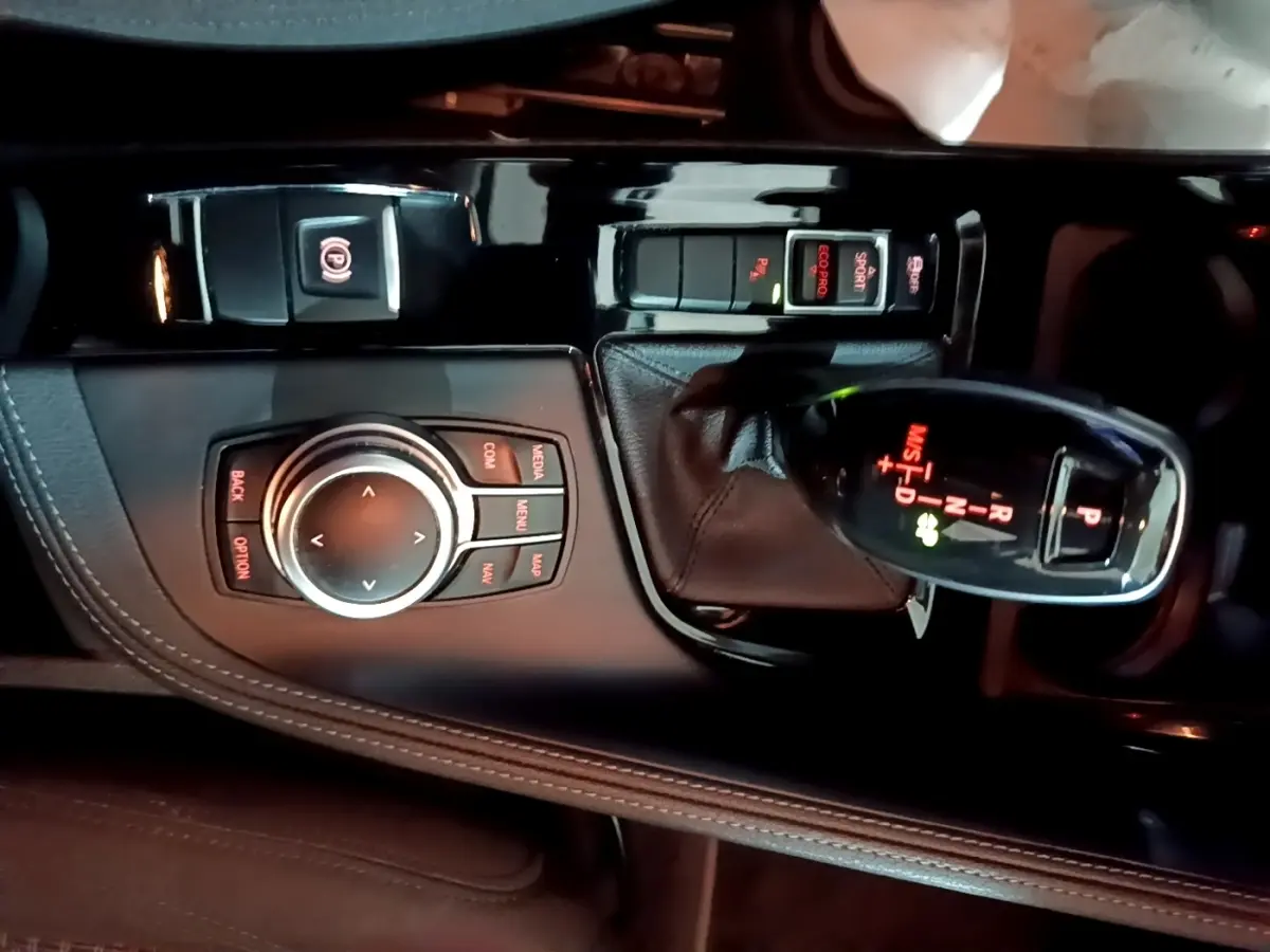 Vue rapprochée de la console centrale noire du BMW X2 2023 avec levier de vitesses automatique et molette de commande.