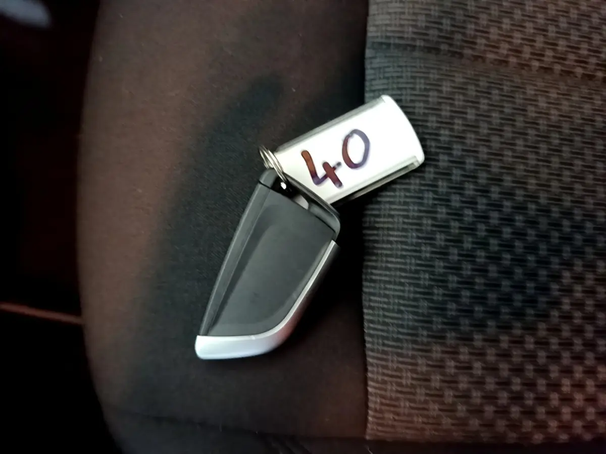 Clé de démarrage BMW posée sur un siège tissu noir à motif, avec étiquette numérotée 40 visible.
