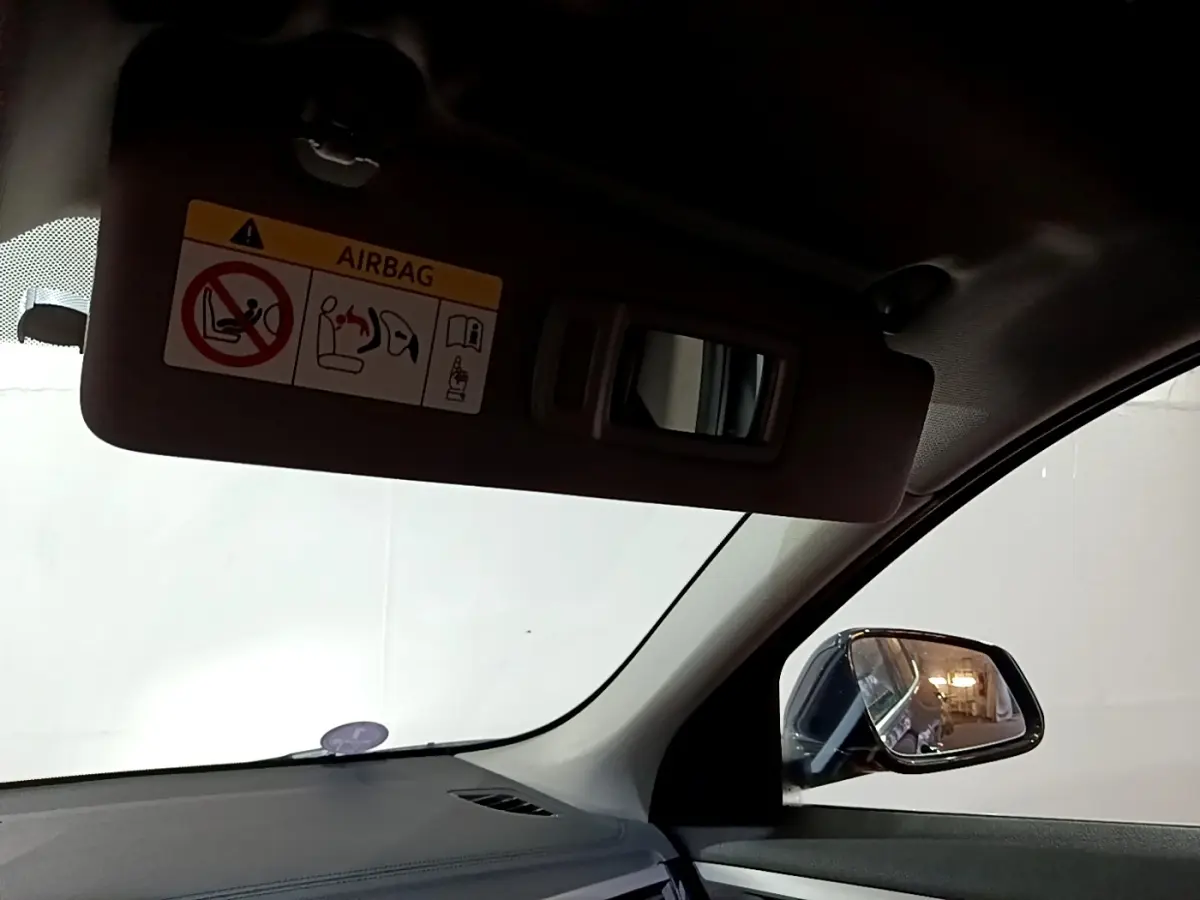 Vue intérieure côté conducteur du BMW X2 noir 2023, avec pare-soleil baissé et rétroviseur extérieur visible.