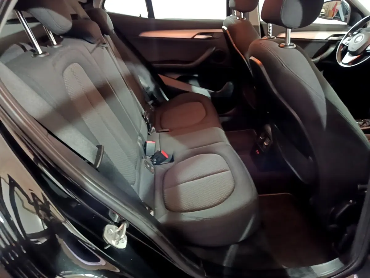 Vue intérieure côté gauche montrant la banquette arrière noire et les sièges avant du BMW X2 sDrive18i Lounge 2023.