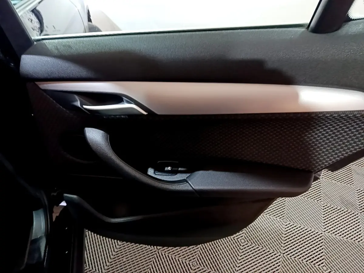 Gros plan sur la porte côté gauche intérieure noire avec insert argenté de la BMW X2 sDrive18i Lounge 2023.