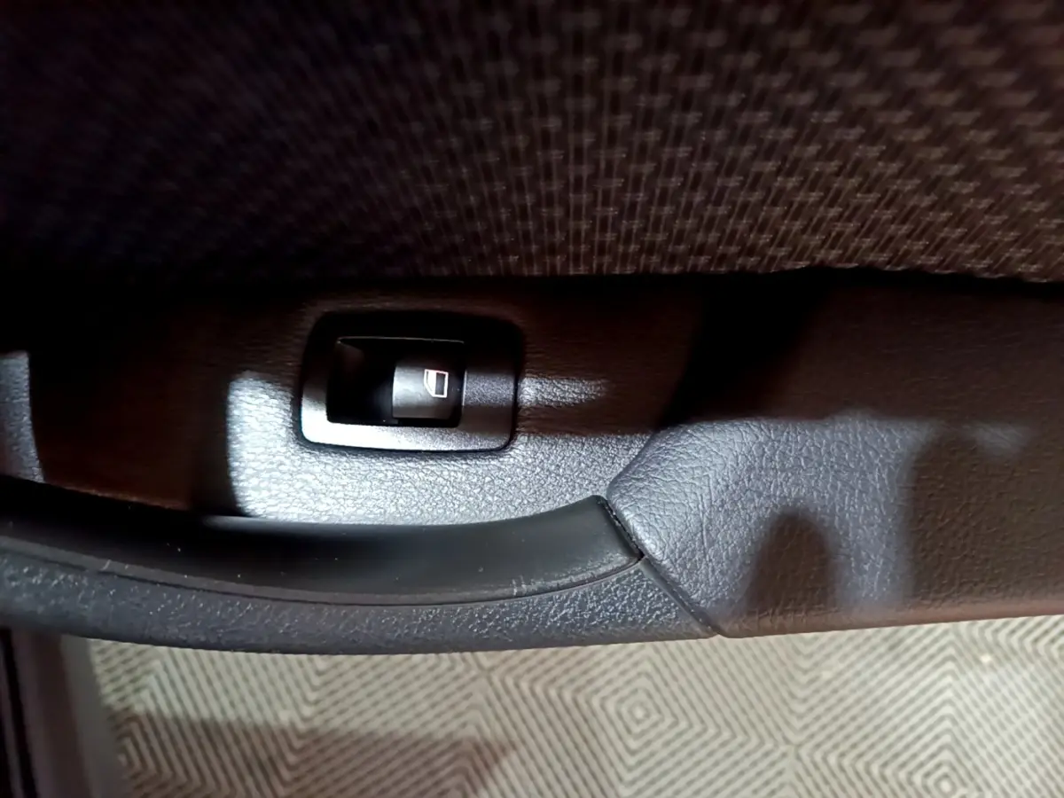 Détail de la commande de lève-vitre noir sur la porte intérieure d'une BMW X2 sDrive18i Lounge 2023.