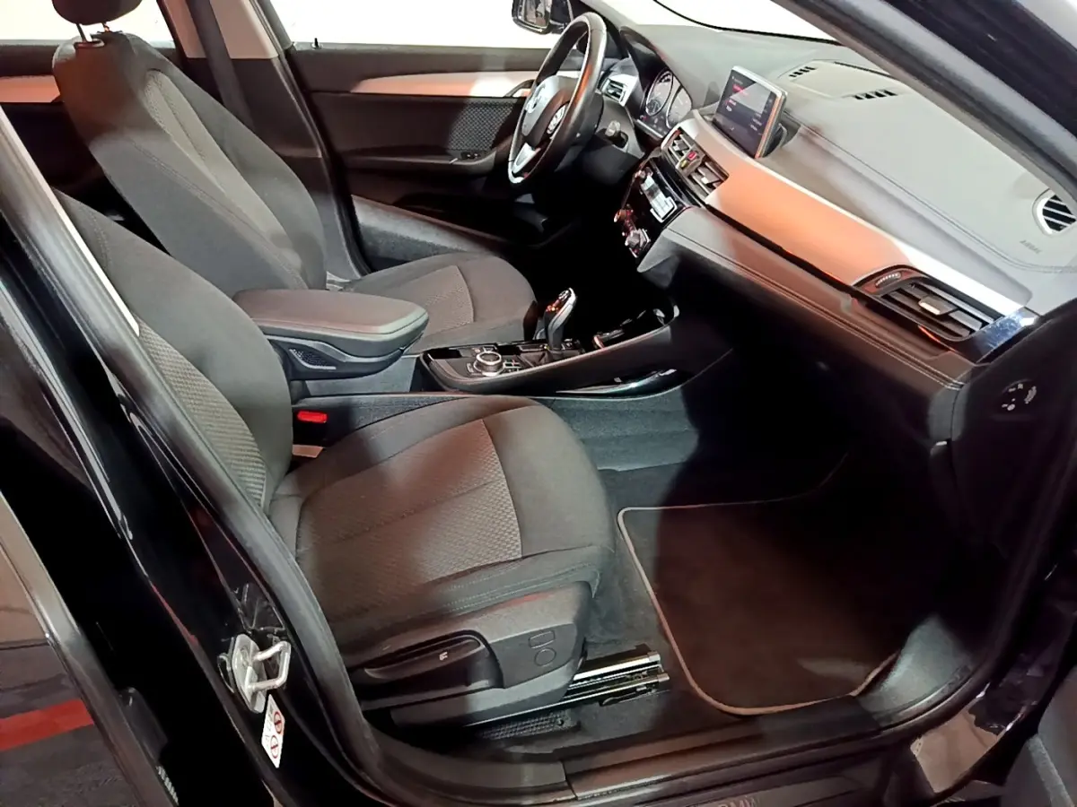 Intérieur avant droit de la BMW X2 sDrive18i Lounge 2023 noir, avec tableau de bord et console centrale visibles.