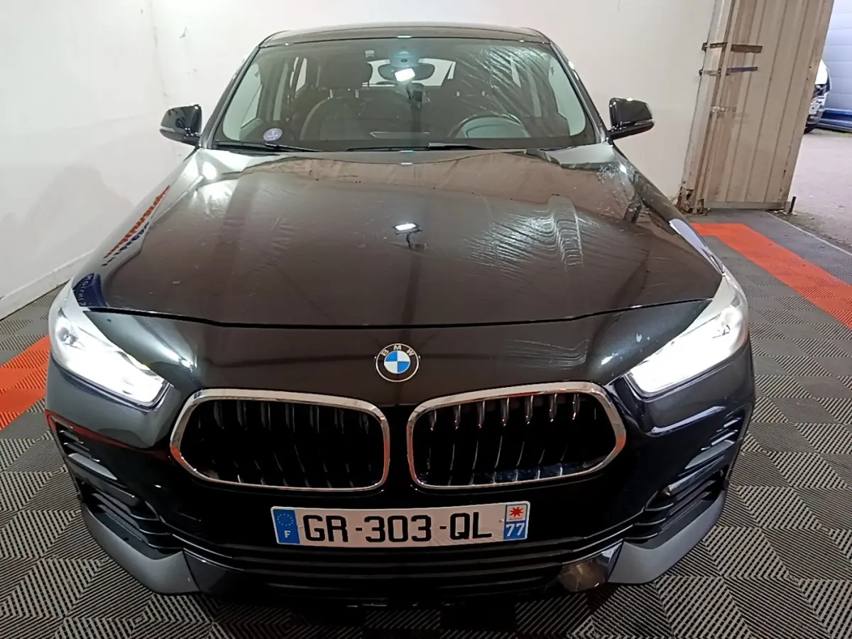Vue frontale d’un BMW X2 noir 2023 avec phares LED allumés et calandre double haricot caractéristique.