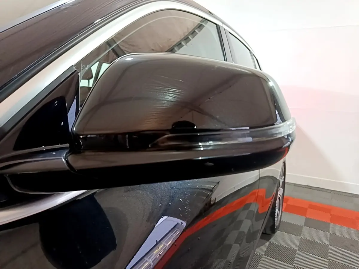 Gros plan sur le rétroviseur côté conducteur noir brillant du BMW X2 sDrive18i Lounge 2023, reflet visible.