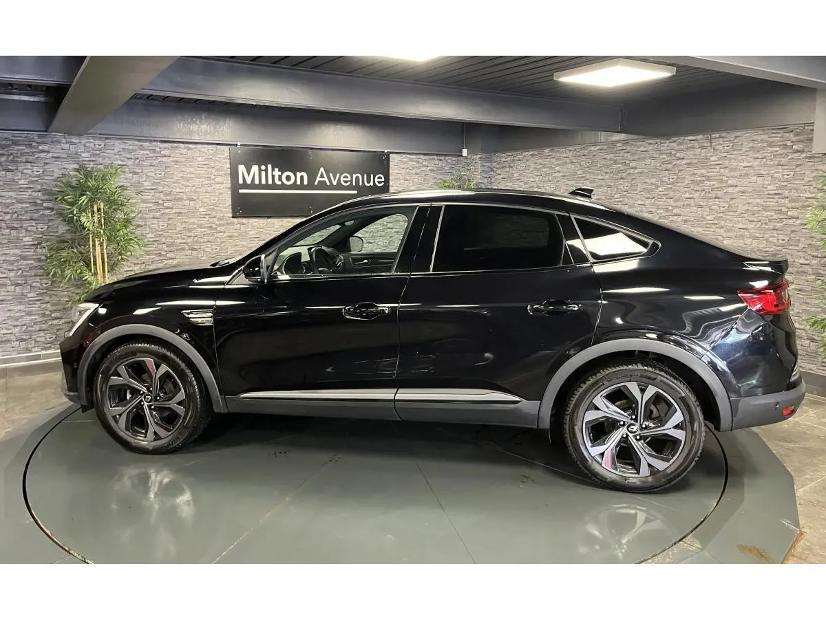 Profil côté gauche d'un Renault Arkana noir métallisé 2023 R.S. Line avec jantes alliage et toit noir.