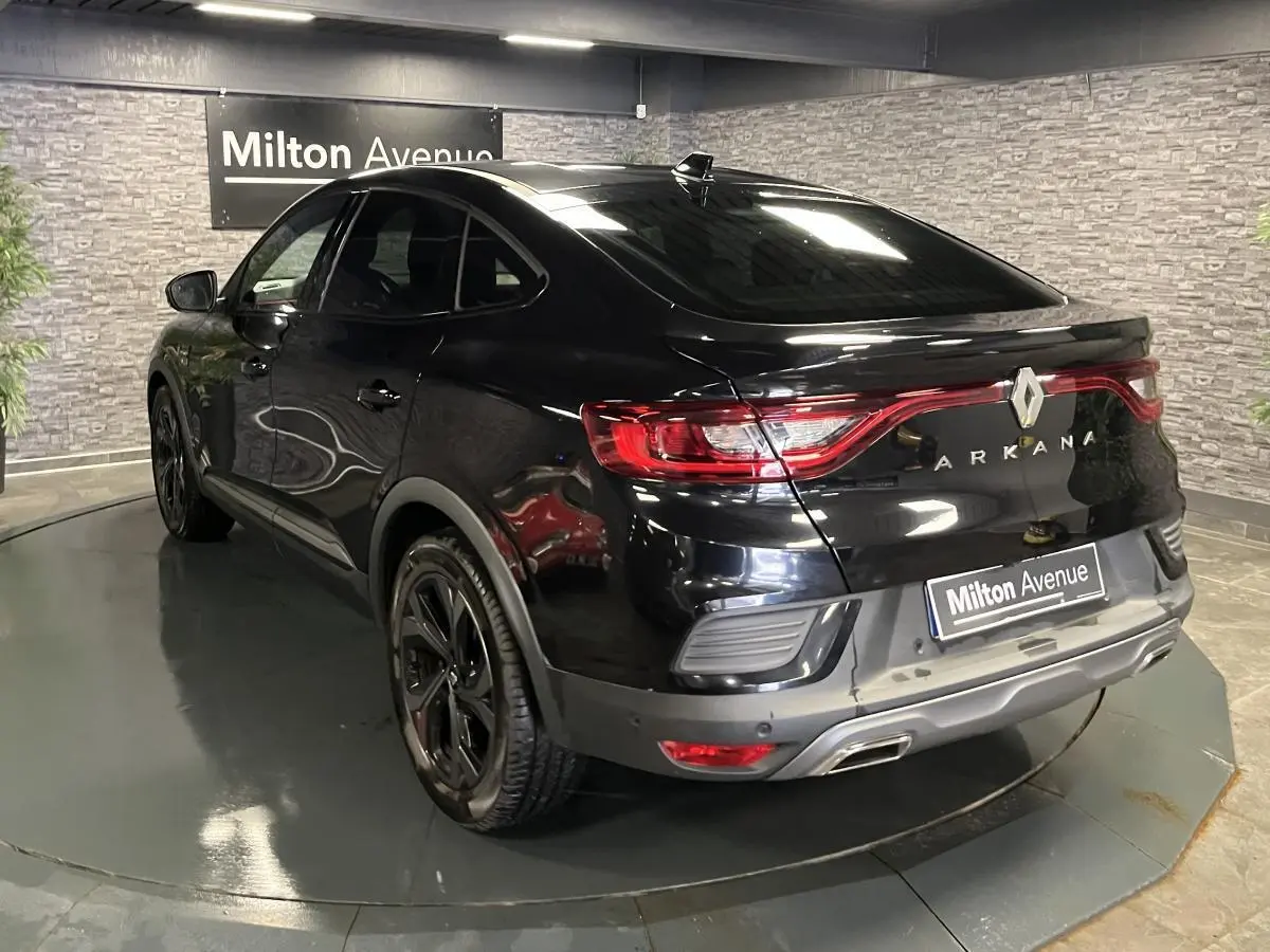Vue 3/4 arrière droite du Renault Arkana noir brillant avec feux arrière reliés et jantes noires sport R.S. Line.