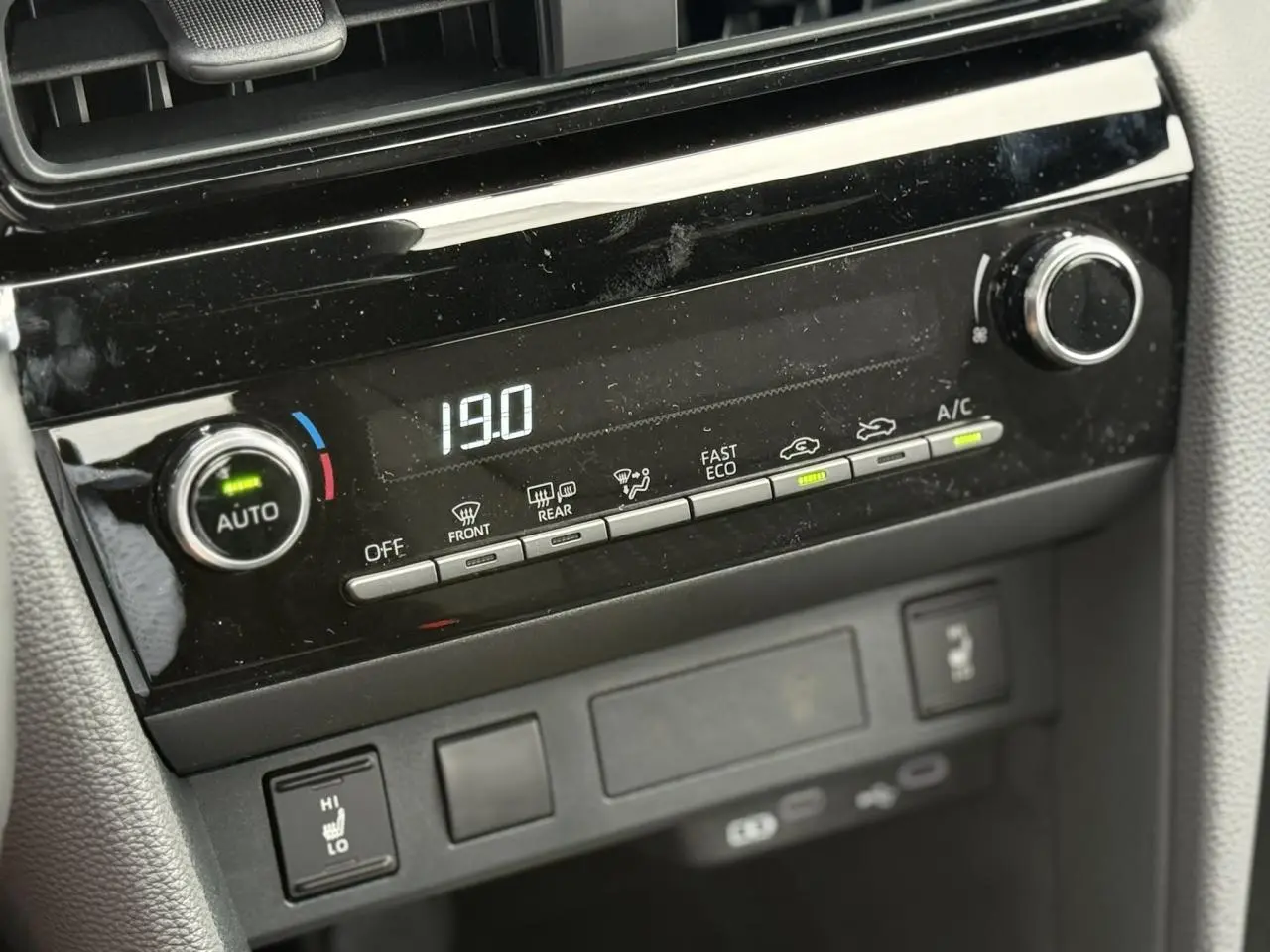 Gros plan sur la console centrale noire brillante de la Toyota Yaris Cross 2026, affichant la climatisation à 19°C.