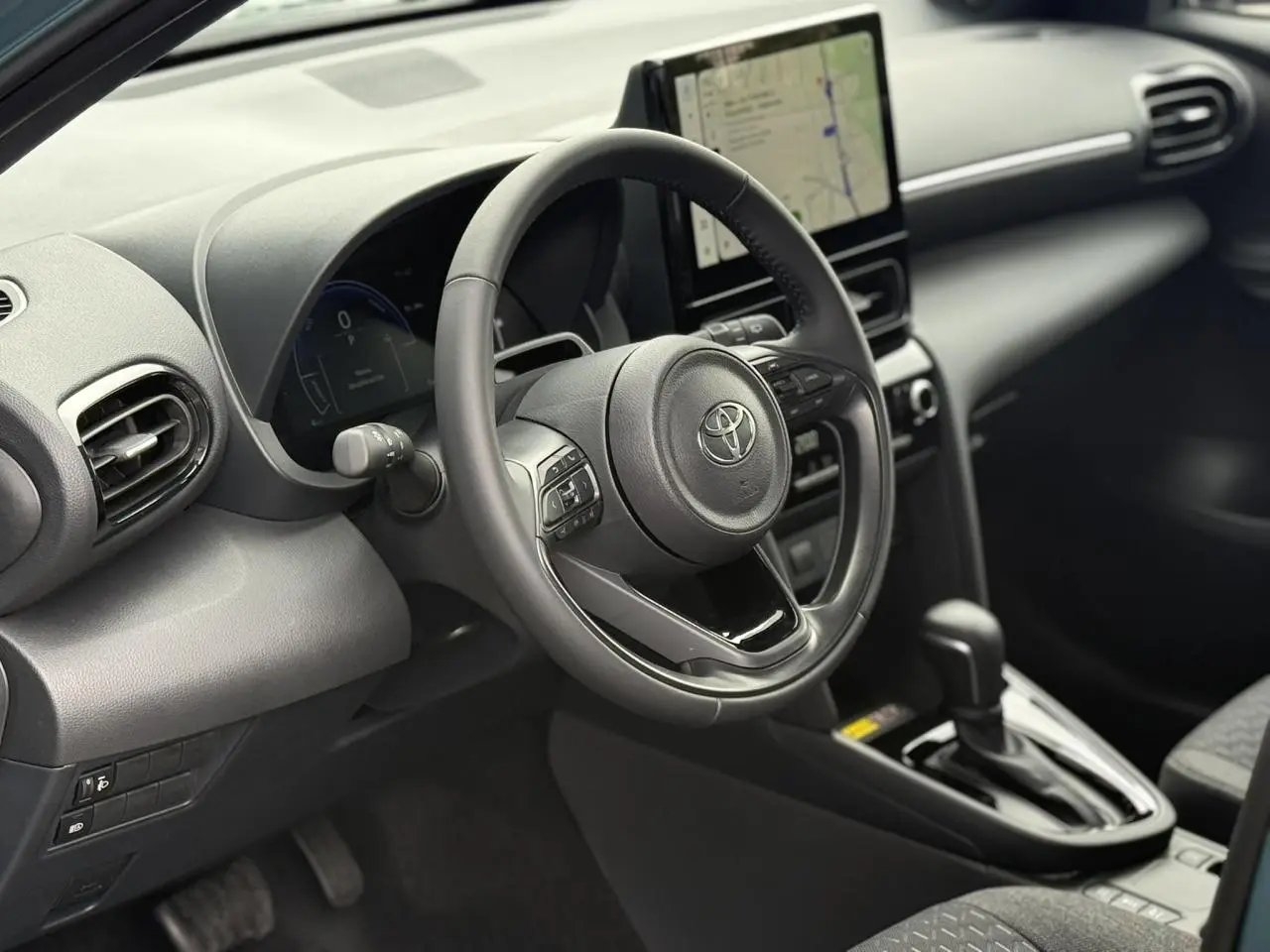 Vue intérieure côté conducteur de la Toyota Yaris Cross 2026, volant cuir et écran tactile central visible.
