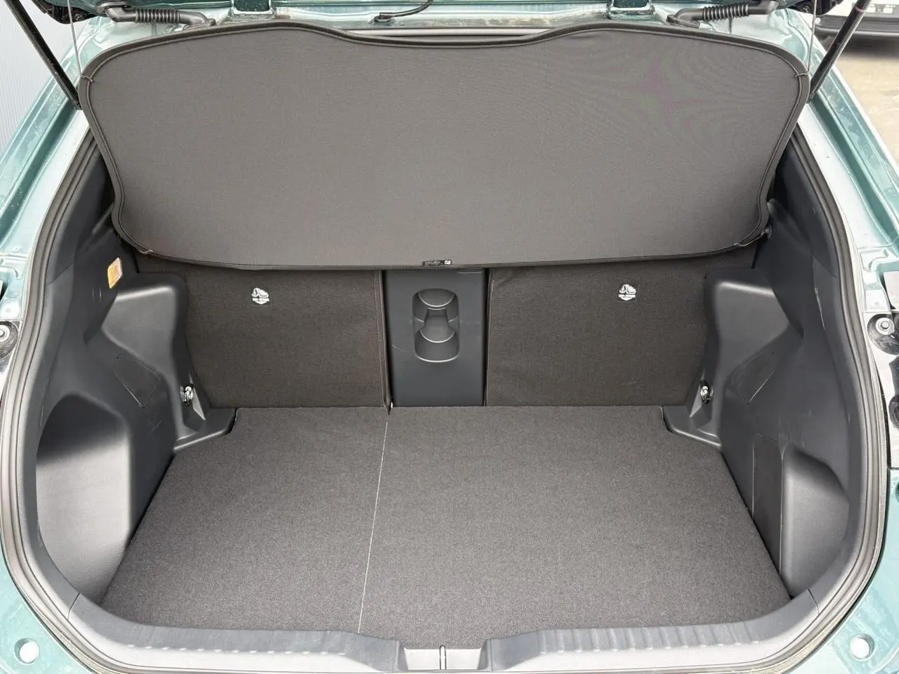 Coffre ouvert de la Toyota Yaris Cross 1.5 Hybrid 2026 en Vert Impérial, montrant un plancher plat et un cache-bagages déployé.