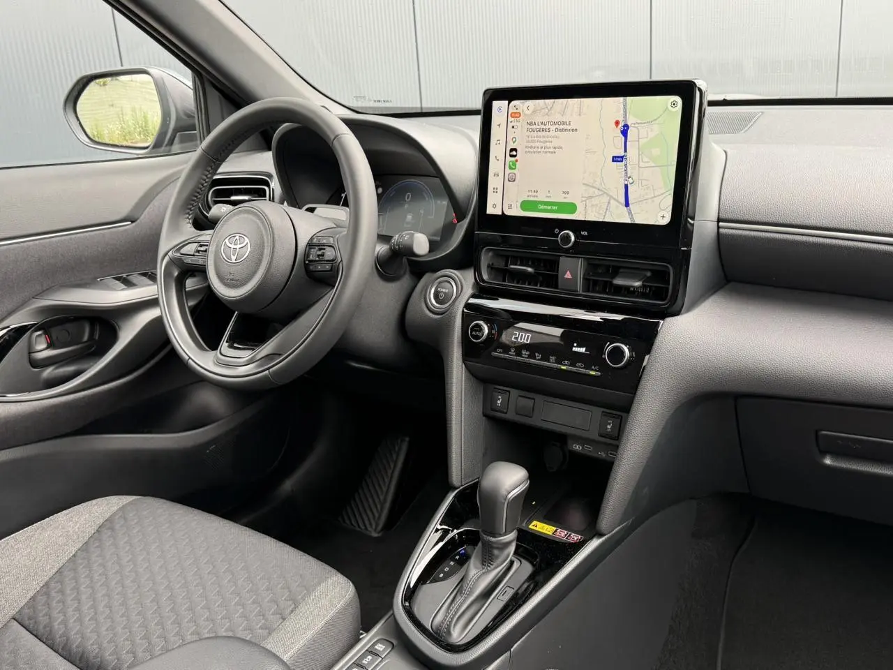 Vue intérieure côté conducteur de la Toyota Yaris Cross 1.5 Hybrid 116 Design avec écran tactile et volant cuir noir.