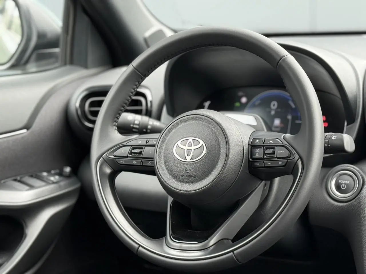 Vue rapprochée du volant cuir noir de la Toyota Yaris Cross 1.5 Hybrid 116 Design avec commandes intégrées.