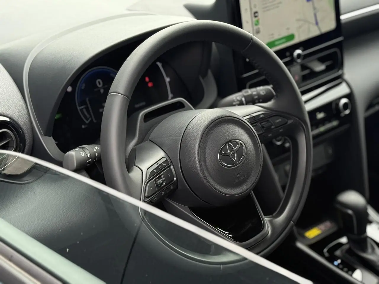 Vue intérieure rapprochée du volant cuir noir et tableau de bord de la Toyota Yaris Cross 1.5 Hybrid 2026.