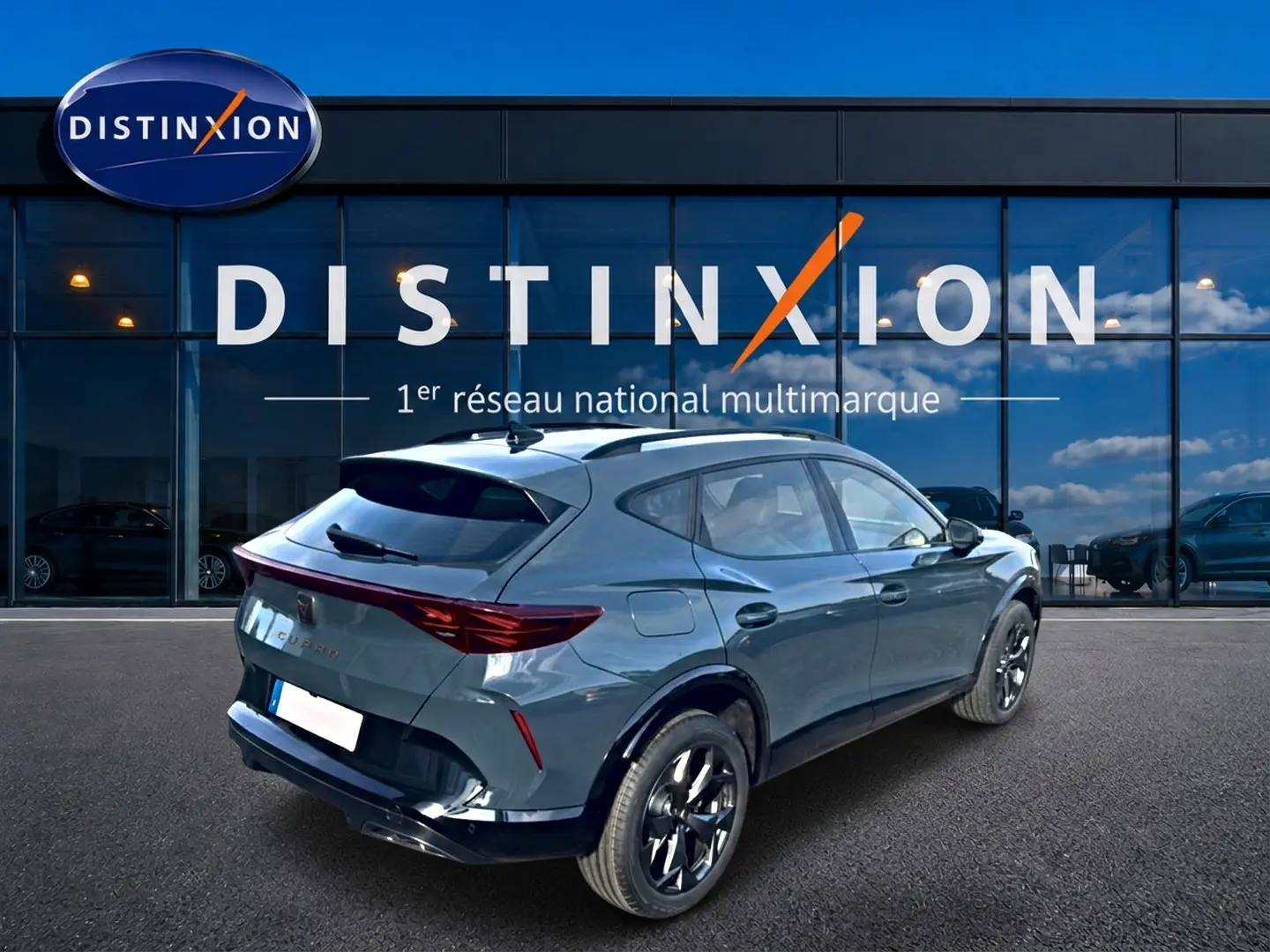 Vue 3/4 arrière droite d'un CUPRA Formentor bleu fjord avec jantes noires, garé devant une vitrine Distinxion.