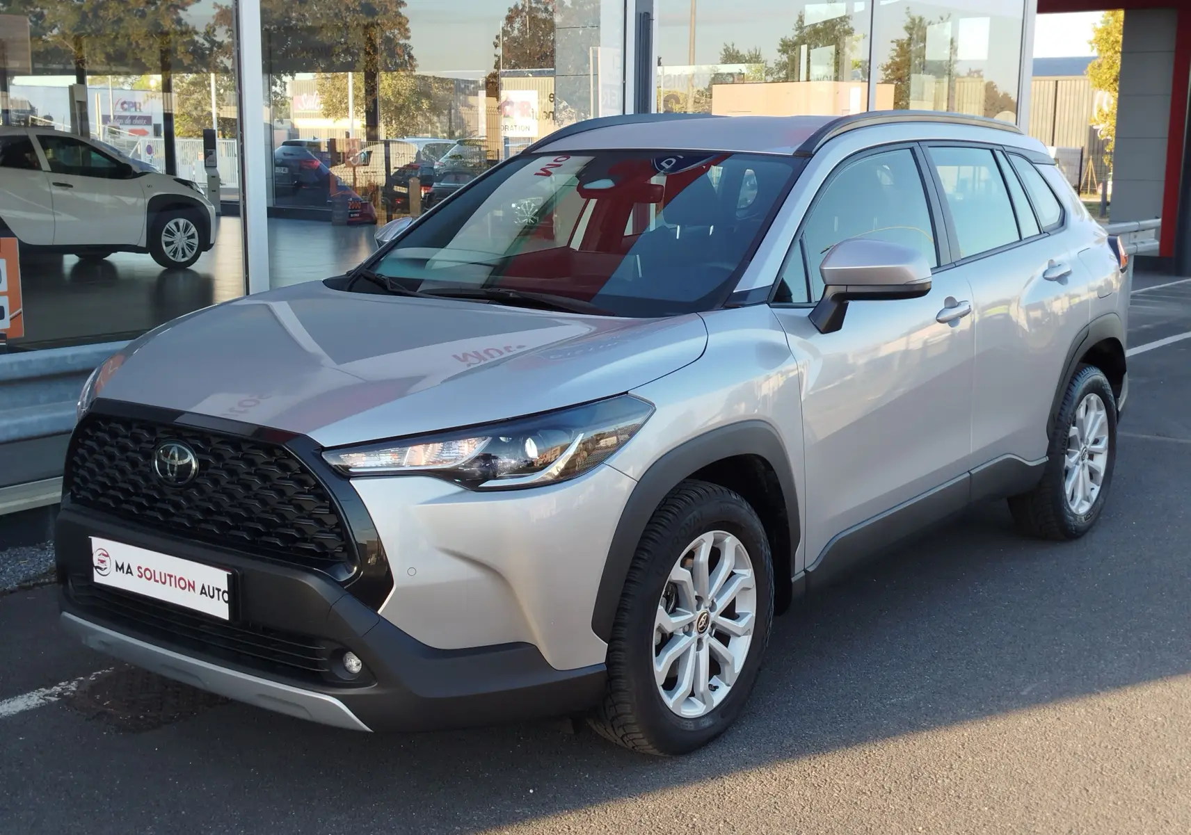 Toyota Corolla Cross gris minéral vue 3/4 avant droit, avec calandre noire et jantes alliage 17 pouces.