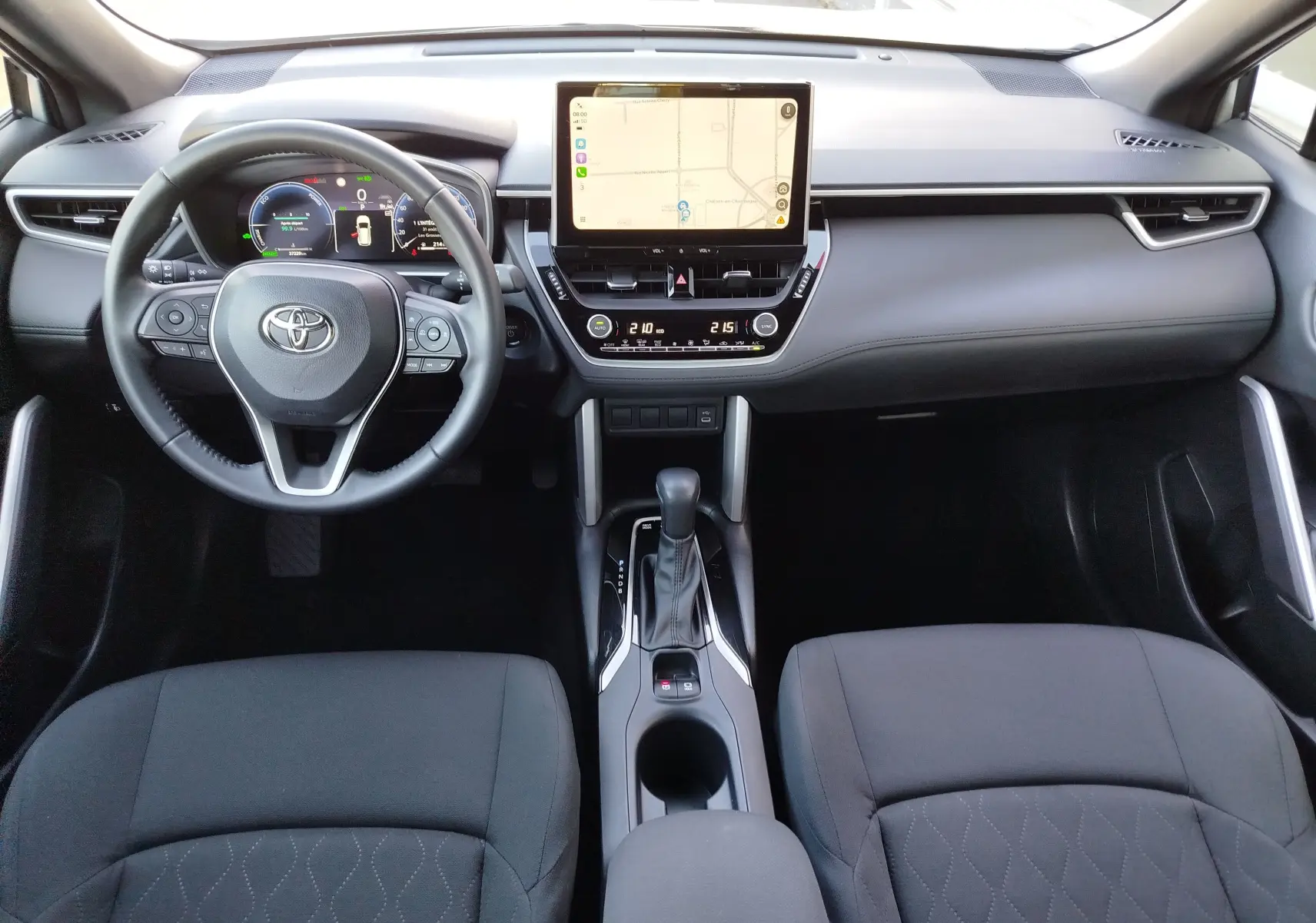 Vue intérieure frontale du tableau de bord de la Toyota Corolla Cross 2025, avec écran tactile central et volant multifonction.