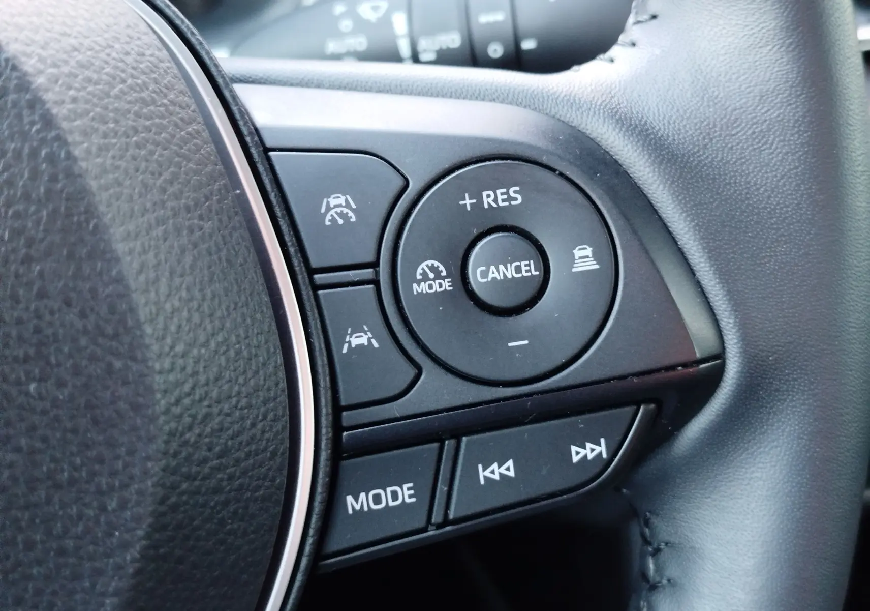 Gros plan sur les commandes noires du volant côté droit du Toyota Corolla Cross gris minéral, boutons de régulateur et multimédia.