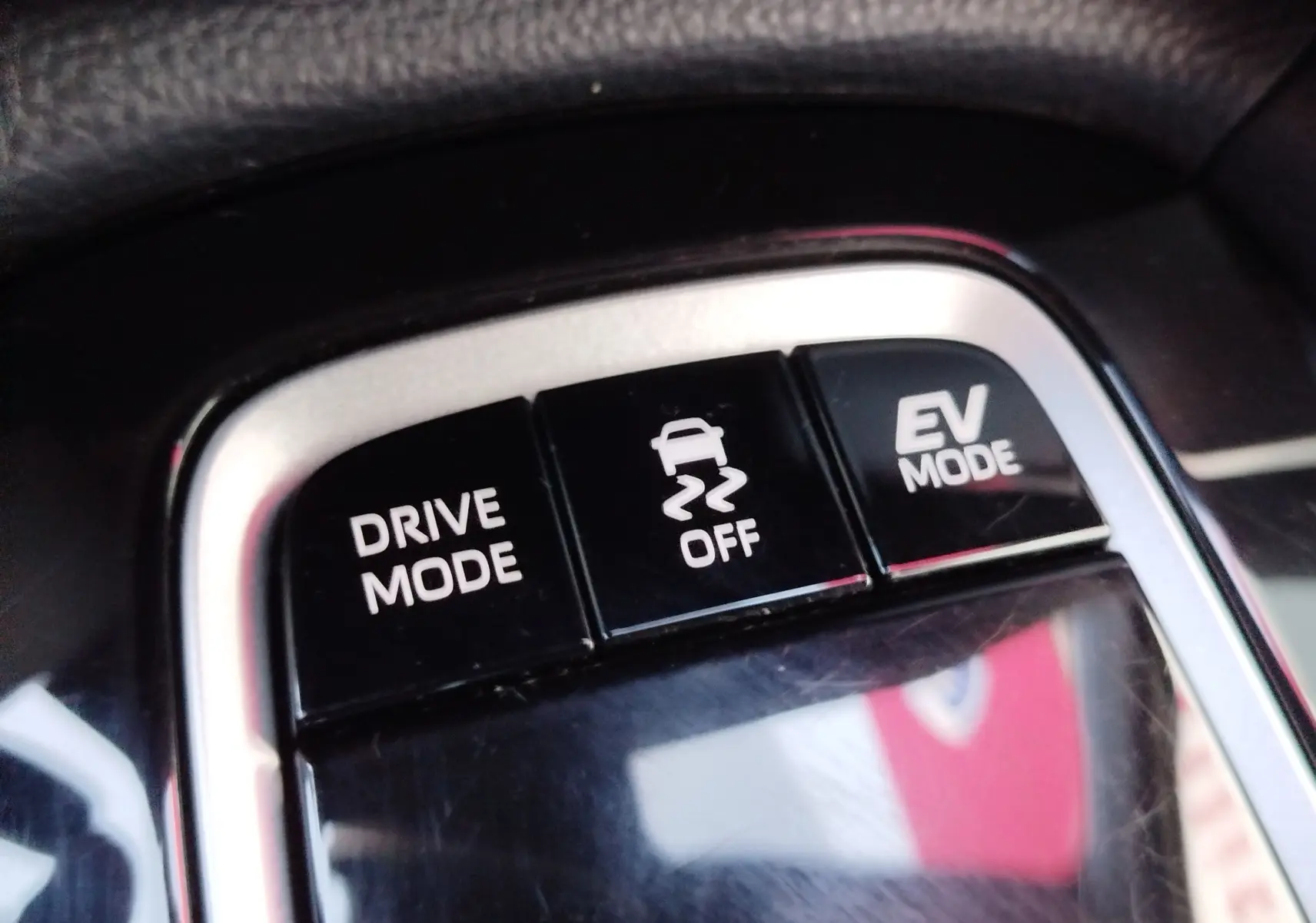 Gros plan sur les boutons de commande du mode de conduite et mode EV dans l'habitacle de la Toyota Corolla Cross gris minéral 2025.
