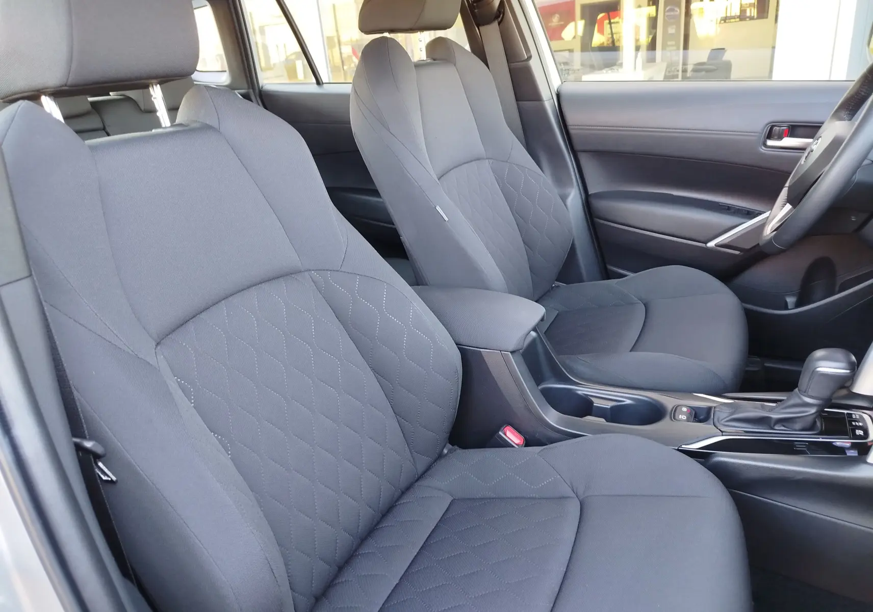 Vue intérieure côté droit sur les sièges avant gris tissu et la console centrale de la Toyota Corolla Cross 2025.