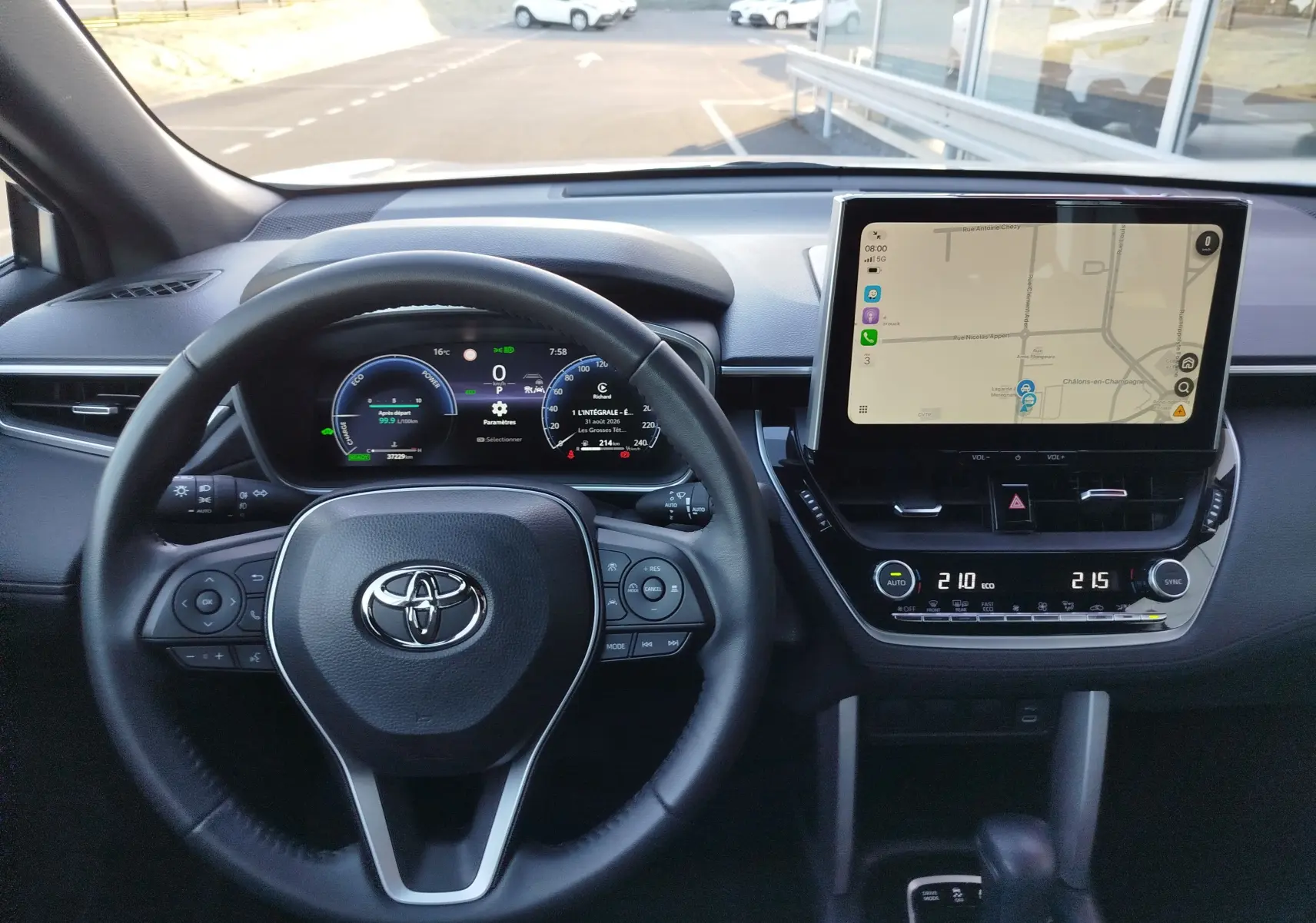 Vue intérieure centrée sur le volant et le tableau de bord numérique de la Toyota Corolla Cross 2025, avec écran tactile et commandes intégrées.